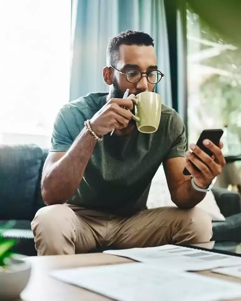 tech - sitting man drinking coffee looking at phone